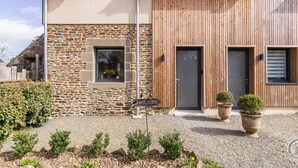 Ein modernes Haus mit einer Stein-Fassade, Holzverkleidung und einem Willkommensschild.