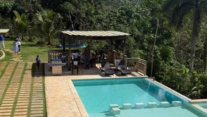 A swimming pool with lounge chairs and a covered seating area surrounded by greenery. - Discover a place for vacations, weekend getaways, or a complete escape. (Don Juan)
