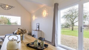 Et moderne spiseområde med et træbord, en elkedel og en bakke med kopper.