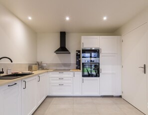 A modern kitchen with white cabinets, a black range hood, and a built-in oven. - House with parking, nature retreat - 4 guests (Céaux)