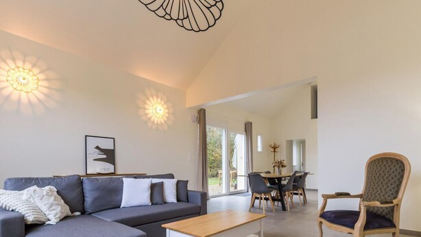 En moderne stue med sofa, sofabord og spiseplads med stole.
