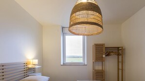 Et soveværelse med en seng, sengeborde med lamper, et vindue og en træhylde.