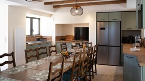 A modern kitchen with a built-in refrigerator, wooden cabinets, and a dining area with a table set for four.