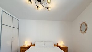 Une chambre à coucher avec un lit, deux lampes de chevet, une couvre-lit jaune et un luminaire au plafond.