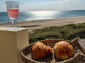 A glass of pink drink, two croissants, and a wicker basket on a balcony overlooking a beach. - Sea view apartment - 2 guests (Barneville-Carteret)