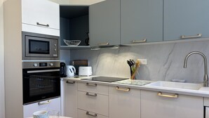 Et moderne køkken med indbyggede hårde hvidevarer, vask og spiseplads.