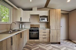 Una cucina compatta con forno a microonde integrato, piano cottura a gas e piccolo forno.