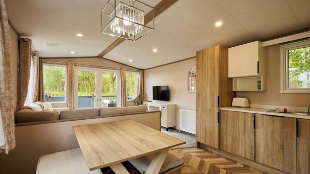 A cozy interior with a seating area, a wooden dining table, a kitchen with wooden cabinets, and a TV.