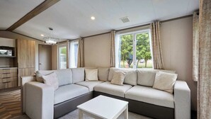 A modern living room with a sectional sofa, a small white table, and a window with curtains.