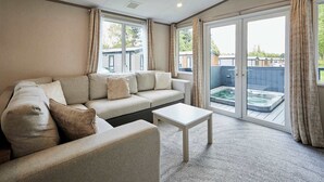 A living room with a sofa, a coffee table, and a hot tub visible through the glass doors.