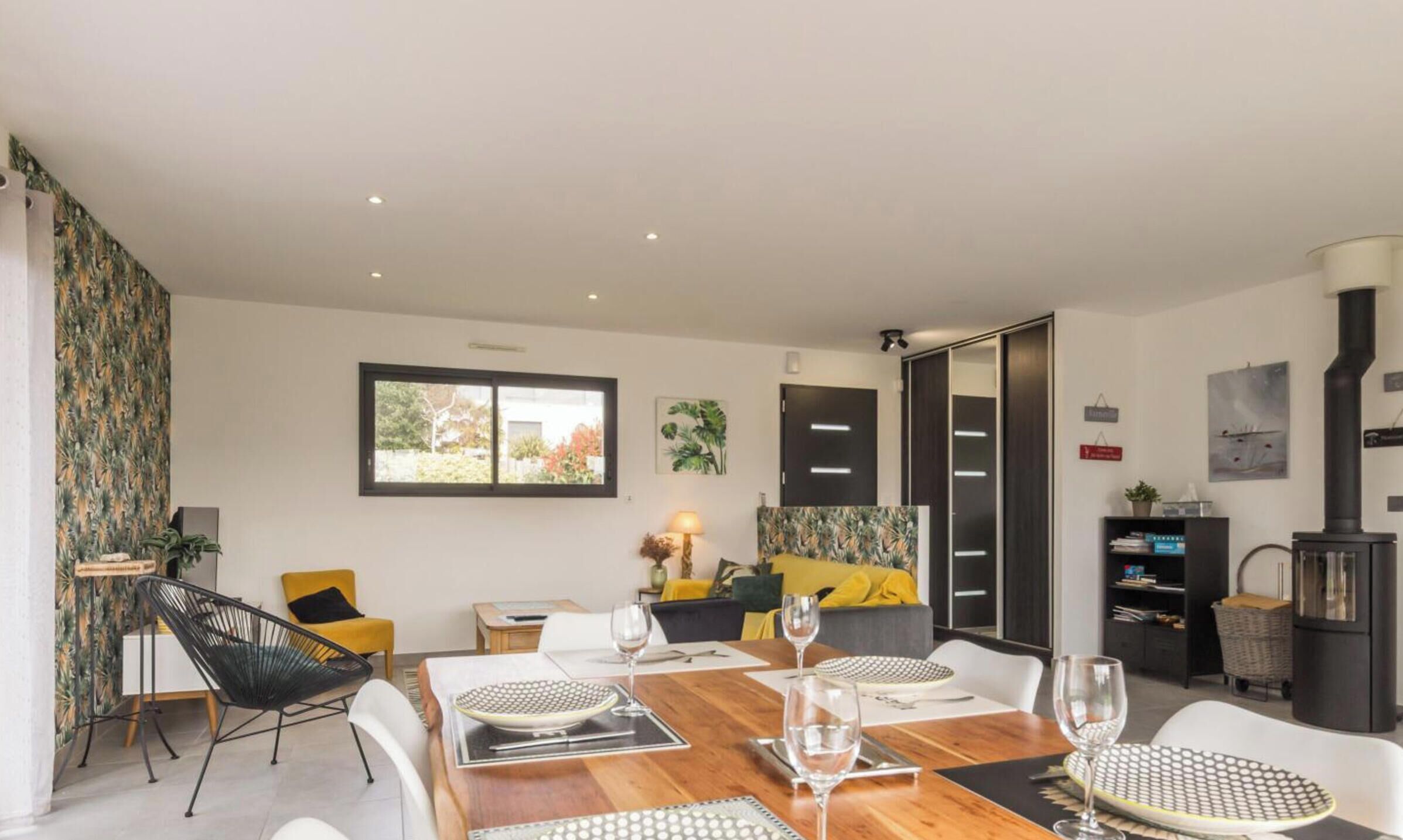 Un comedor moderno con una mesa de madera, sillas blancas y vistas al exterior a través de un ventanal.