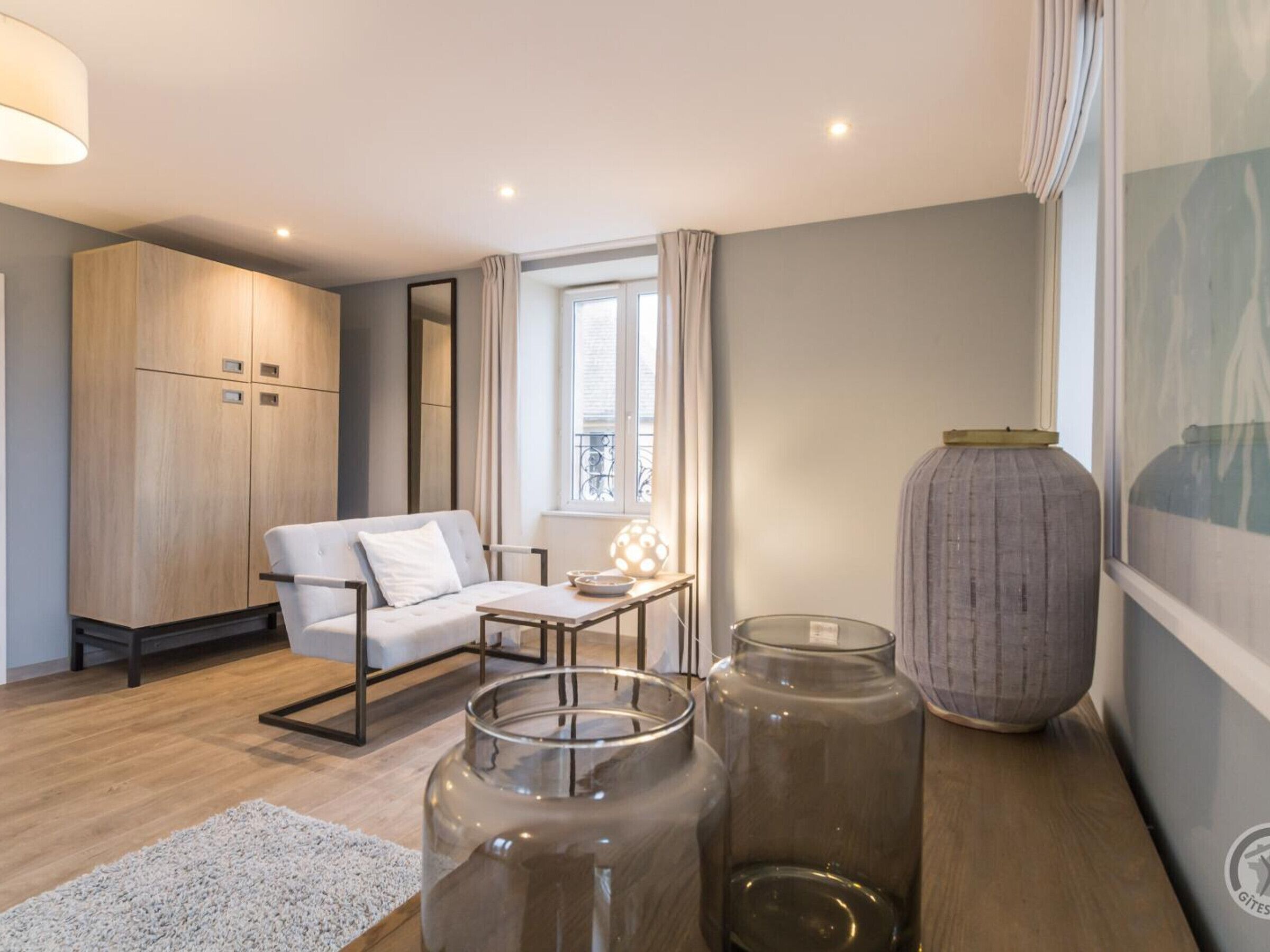 Un salon moderne avec un canapé, une table, un grand vase et une armoire.