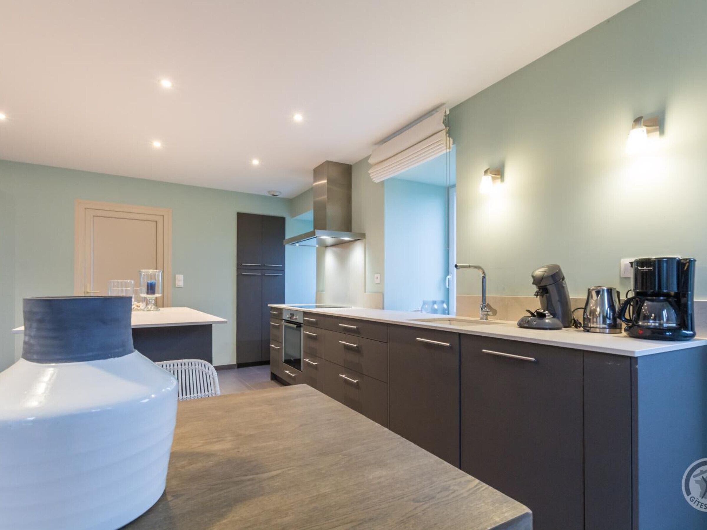 A modern kitchen with a built-in oven, a coffee maker, and a water dispenser.