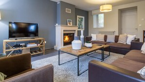 A modern living room with a fireplace, a television, and comfortable seating. - Detached house with panoramic view - 8 guests (Portbail)