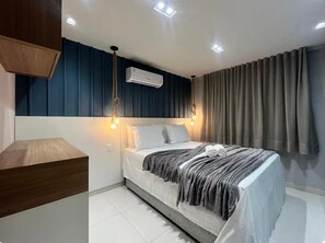 Ein modernes Schlafzimmer mit einem Bett, Nachttischlampen, einer Klimaanlage und einem Holztisch.