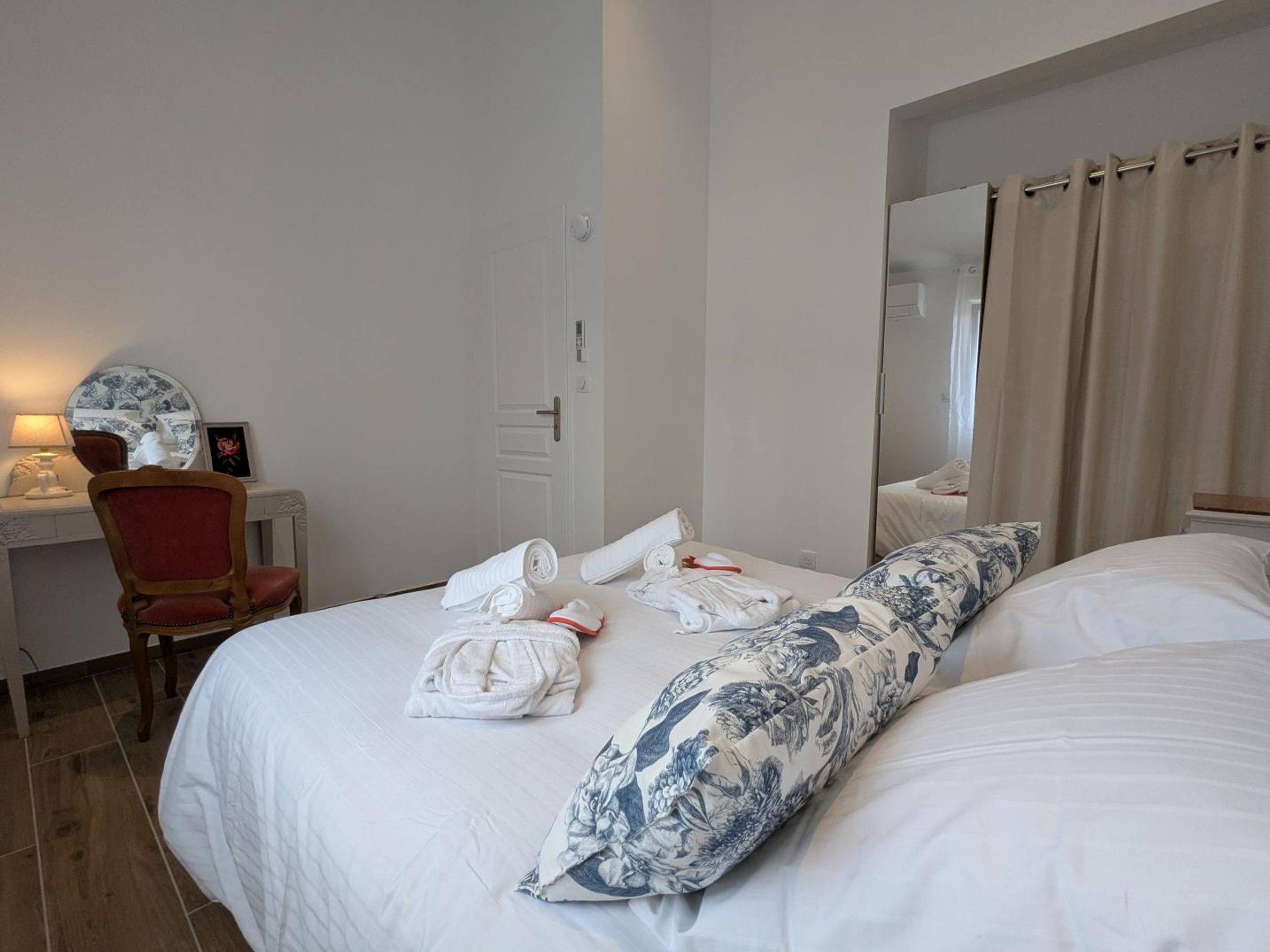 A hotel room with a bed, a chair, a desk, and a mirror.