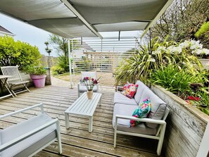 An outdoor patio with a white sofa, a white table, and a white chair. There is a pergola with a white lattice structure and a white canopy overhead. - Cosy house near the sea - 2 guests (Barneville-Carteret)