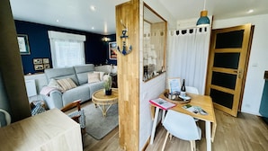 Un espacio habitable compacto con sofá, mesa de comedor y espejo.