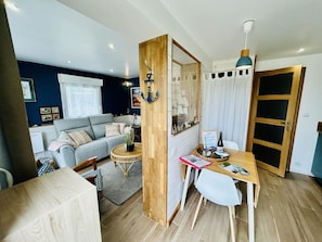 A compact living space with a sofa, dining table, and a mirror. - Cosy house near the sea - 2 guests (Barneville-Carteret)