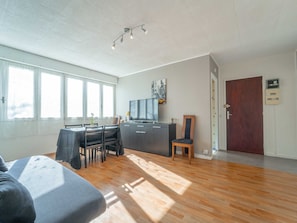 Un amplio espacio de sala con una mesa de comedor, sillas, un sofá, un televisor y una puerta de madera.