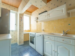 Una cocina compacta con estufa, horno, pileta y gabinetes blancos.