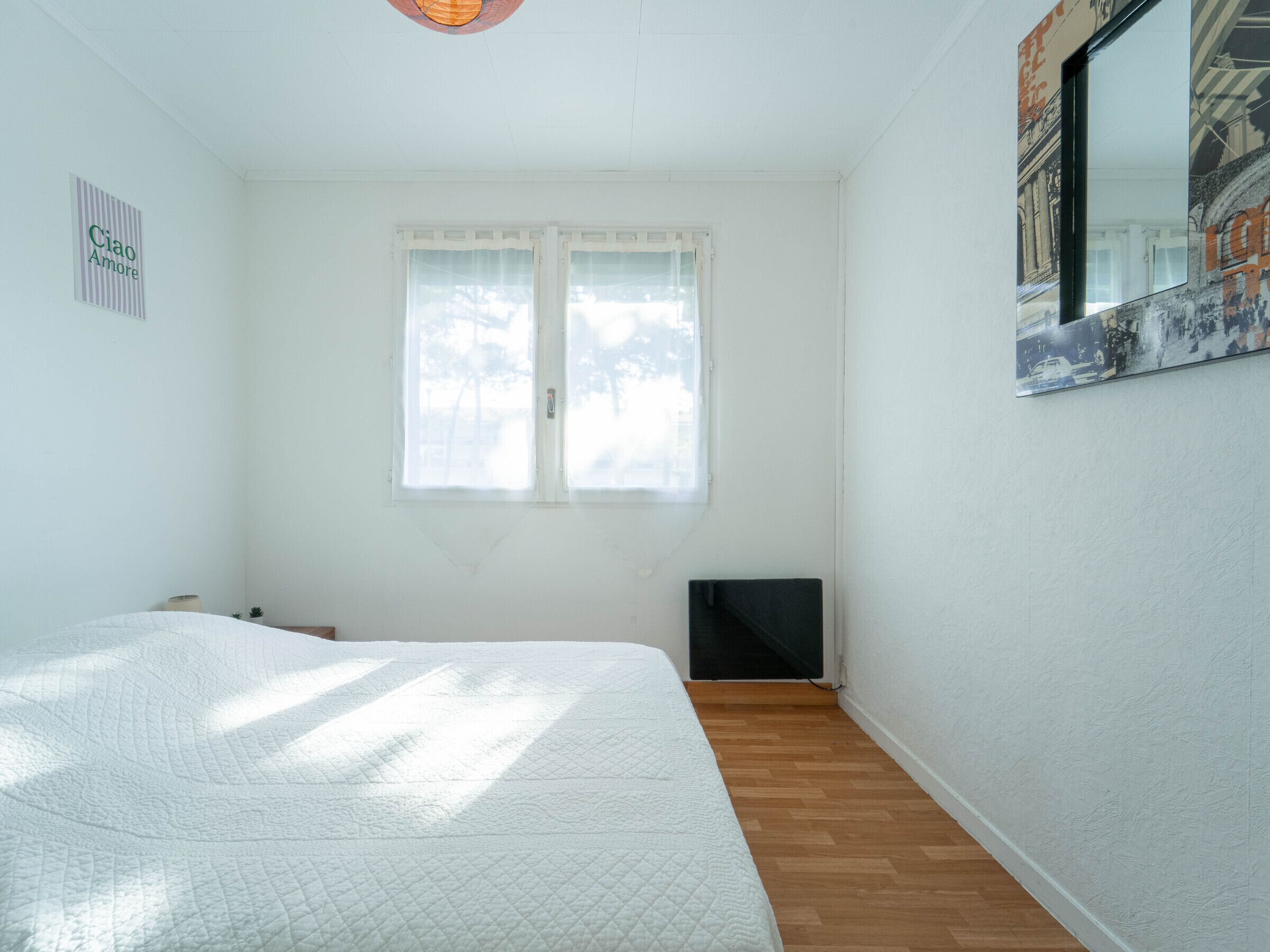 Un dormitorio con cama, ventana, radiador y espejo fijado a la pared.