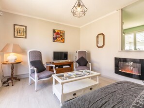 A modern living room with two armchairs, a TV, a fireplace, and a coffee table.