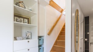 Eine Treppe mit Holzboden und Geländer, die zu einem Raum mit weißen Wänden und Fliesenboden führt.