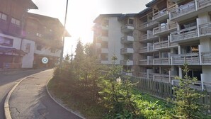 Um edifício de vários andares com varandas, uma rua e um poste de luz.