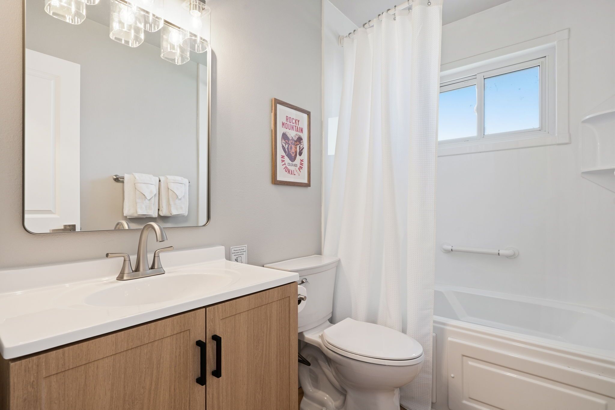 A bathroom with a sink, mirror, toilet, and bathtub.