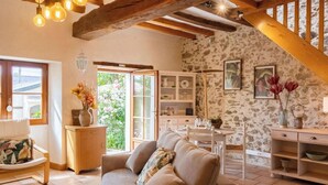 Una sala acogedora con un sofá, una mesa de comedor y una escalera.