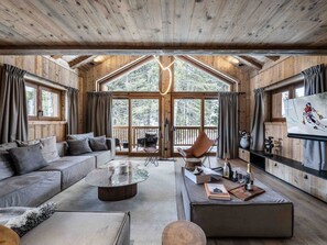 Ein geräumiges Blockhütten-Interieur mit einer großen Holzbalkendecke, einer Couch, einem Couchtisch und einem Fernseher.