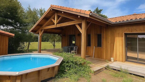 A wooden cabin with a covered patio, a swimming pool, and a deck.
