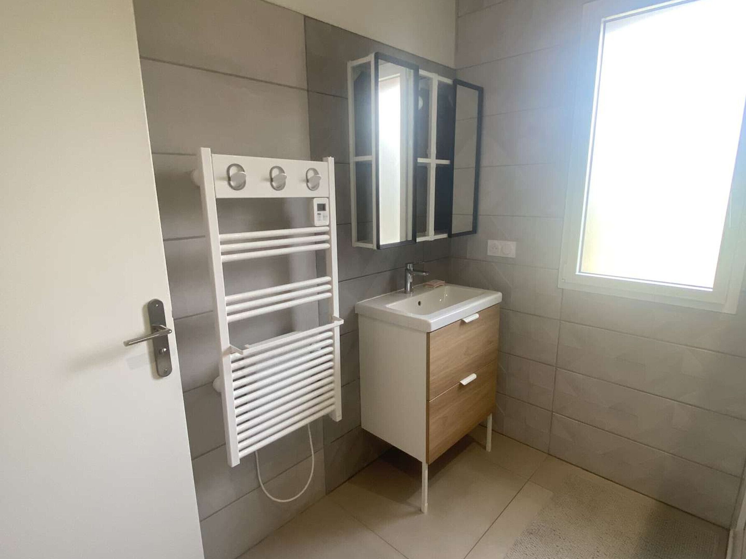 Une salle de bain avec un porte-serviettes blanc, un lavabo et un miroir.