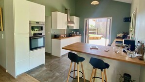 A modern kitchen with white cabinets, a wooden island, and bar stools.