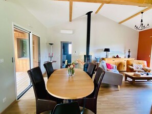Een ruime woonkamer met een eettafel, stoelen, een bank en een open haard.