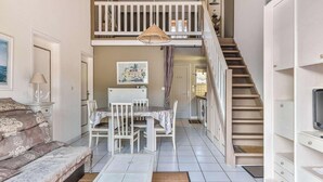 A two-story interior with a dining area, staircase, and a TV on the upper floor. - Duplex with parking, near beach - 6 guests (Biscarrosse)