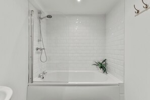 A modern bathroom with a glass-enclosed shower, a white bathtub, and a small potted plant. - Cozy Leeds Hideaway Near the City (Leeds)