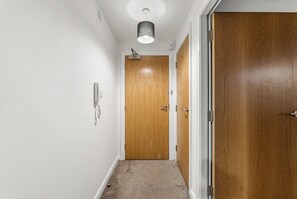 Ein Flur mit Holztür, einer Lampe und Teppichboden.