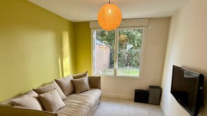 A living room with a sofa, a TV, and a window. - Spacious house, beach 400m away - 12 guests (Carnac)