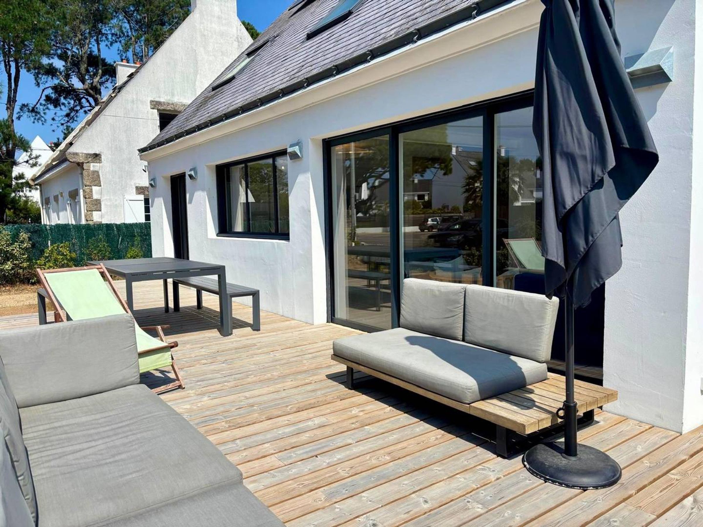 A modern outdoor deck with a sofa, a table, and a patio umbrella.