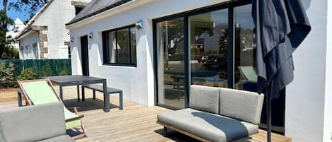 A modern outdoor deck with a sofa, a table, and a patio umbrella.