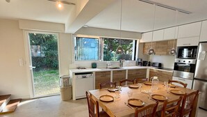 A modern kitchen with a dining area, large windows, and a view of the outdoors. - Spacious house, beach 400m away - 12 guests (Carnac)