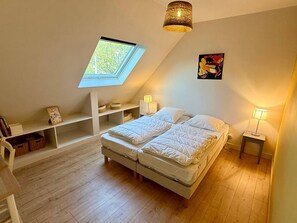 Ein Schlafzimmer mit Oberlicht, einem Bett, Nachttischen und einer Regaleinheit.