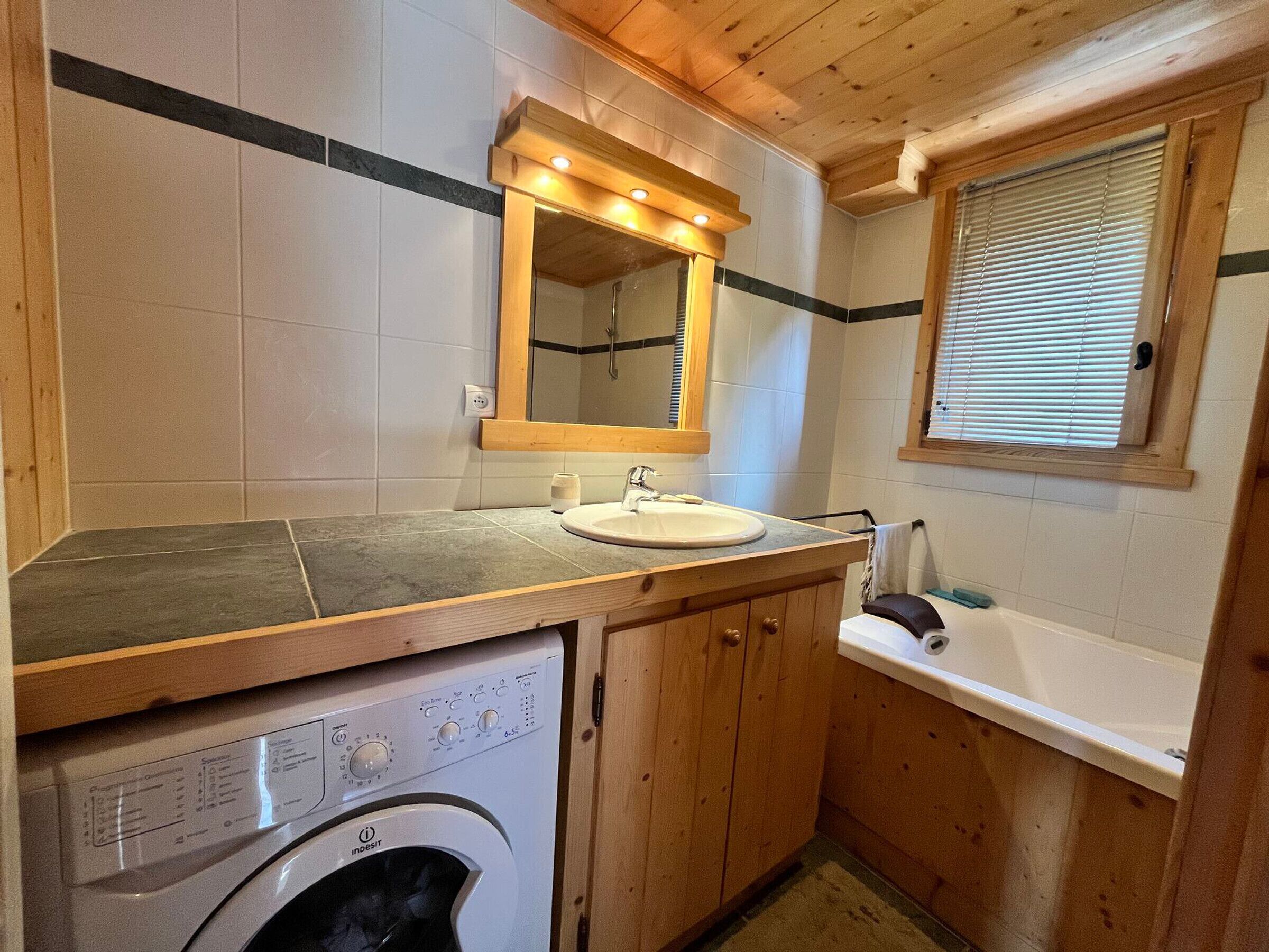 A compact bathroom with a washing machine, a sink, and a bathtub.