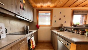A narrow kitchen with wooden cabinets, a stainless steel dishwasher, and a window with blinds. - Apartment with panoramic view - 4 guests (Samoëns)