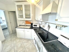 A kitchen with white cabinets, a black countertop, a stove, and a microwave. - Apartment in Roses with terrace, equipped kitchen and private garage (Roses)