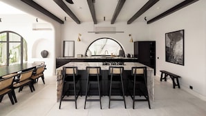 Eine moderne Küche mit einer Marmorinsel, schwarzen Barhocker und Deckenventilatoren.