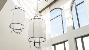 Amplia habitación con techo alto, ventanas grandes y zona de comedor con vista a una piscina.