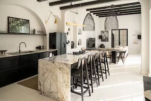 A modern kitchen with a marble island, black cabinetry, and pendant lighting. - Luxurious 3 BR villa, 100 meters from the Beach (Seseh)